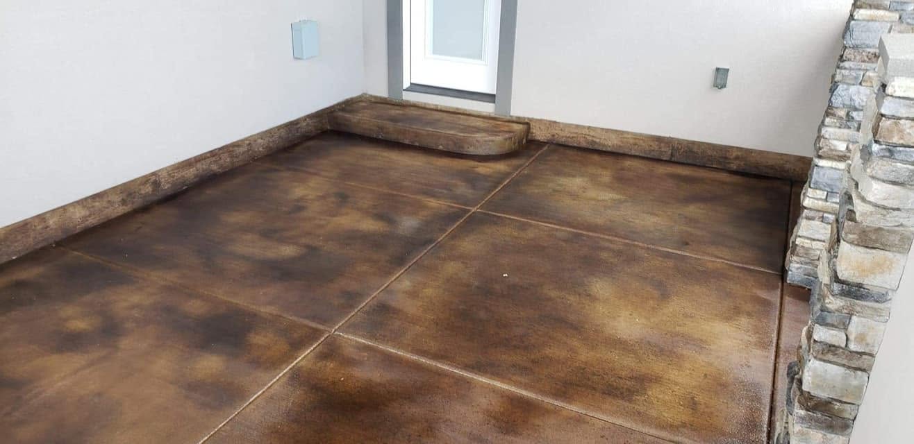 Acid-stained stamped concrete interior floor in warm brown tones with stone accent wall