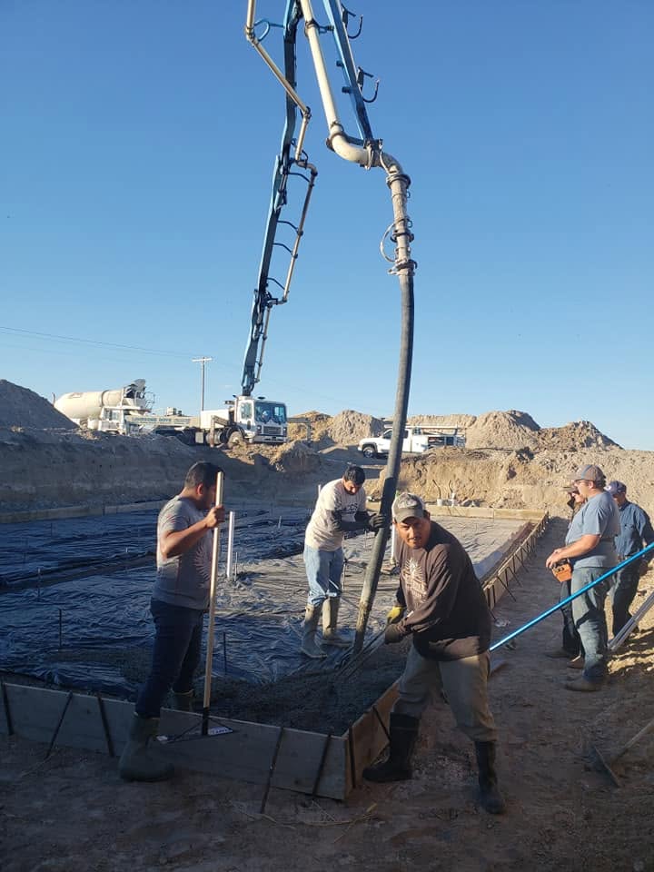 Ramstone crew placing concrete from a boom pump truck into commercial foundation forms