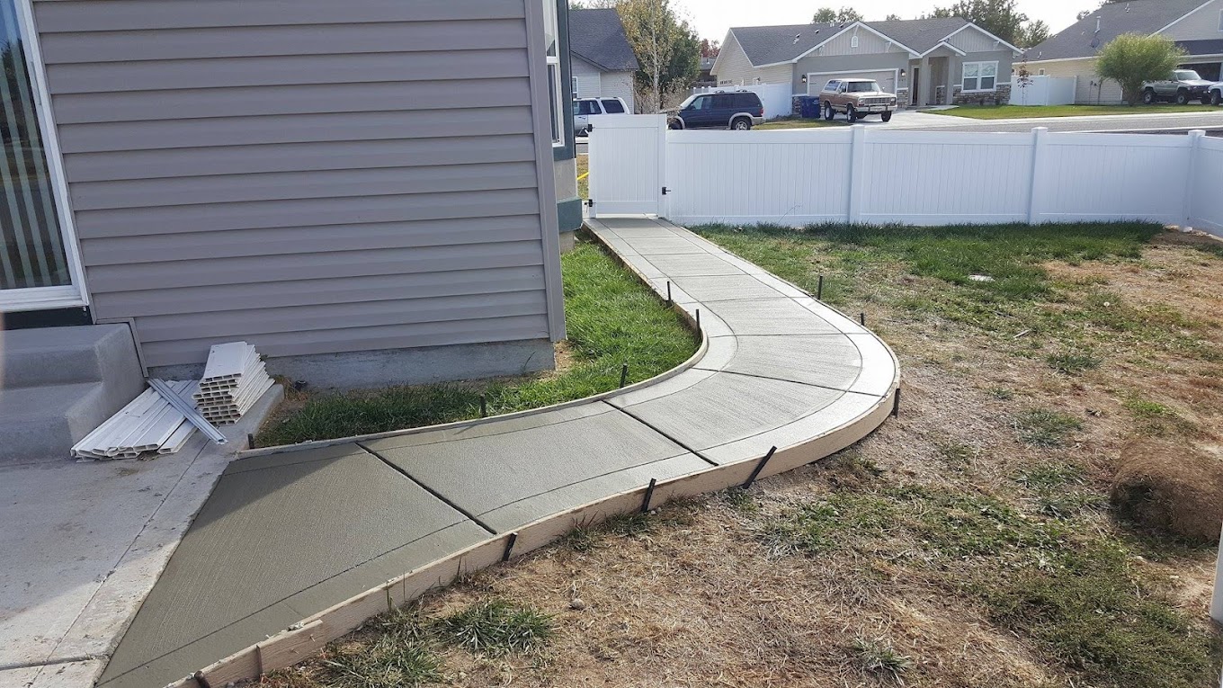 Curved concrete sidewalk leading from a side gate around the corner of a home