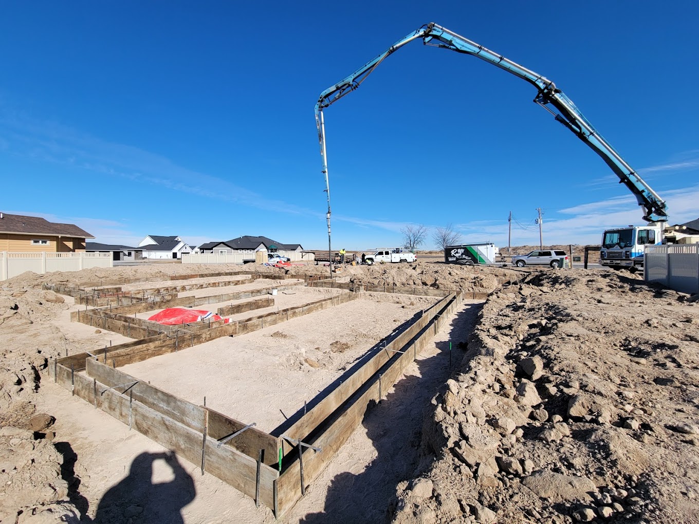 Large-scale commercial foundation pour with formed footings and boom pump truck on site