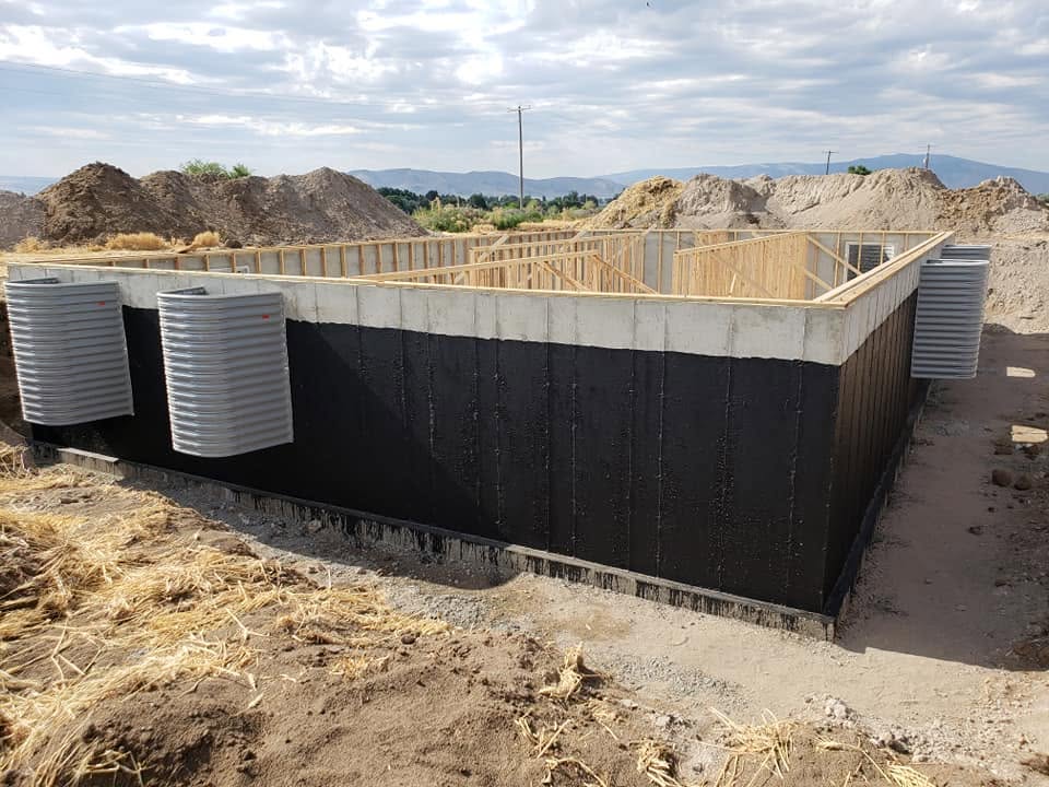 Commercial foundation with waterproofed concrete walls and wood framing under construction