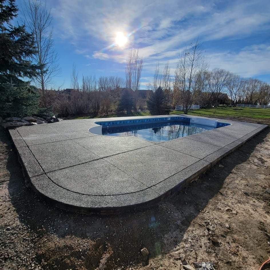 Exposed aggregate concrete pool deck surrounding inground pool